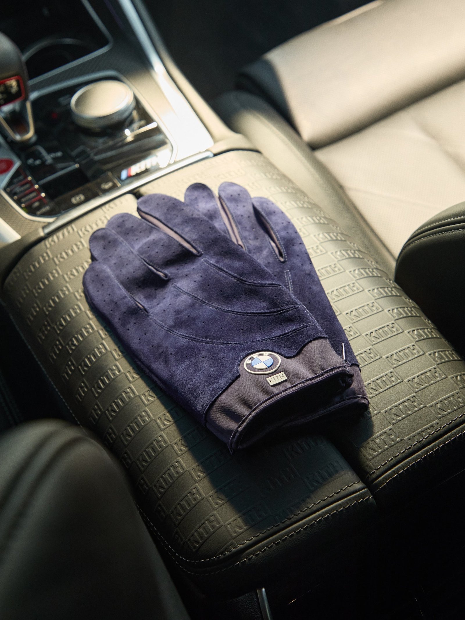BMW 실내에 놓인 보라색 Kith 스웨이드 드라이빙 글러브